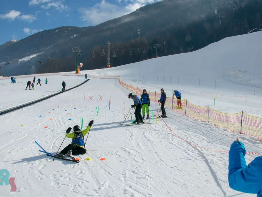 Übungshang mit Markierungen, eine Person sitzt im Schnee.